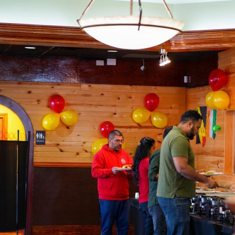Restaurant dining room decorated with red and yellow balloons, where guests serve themselves from a buffet.